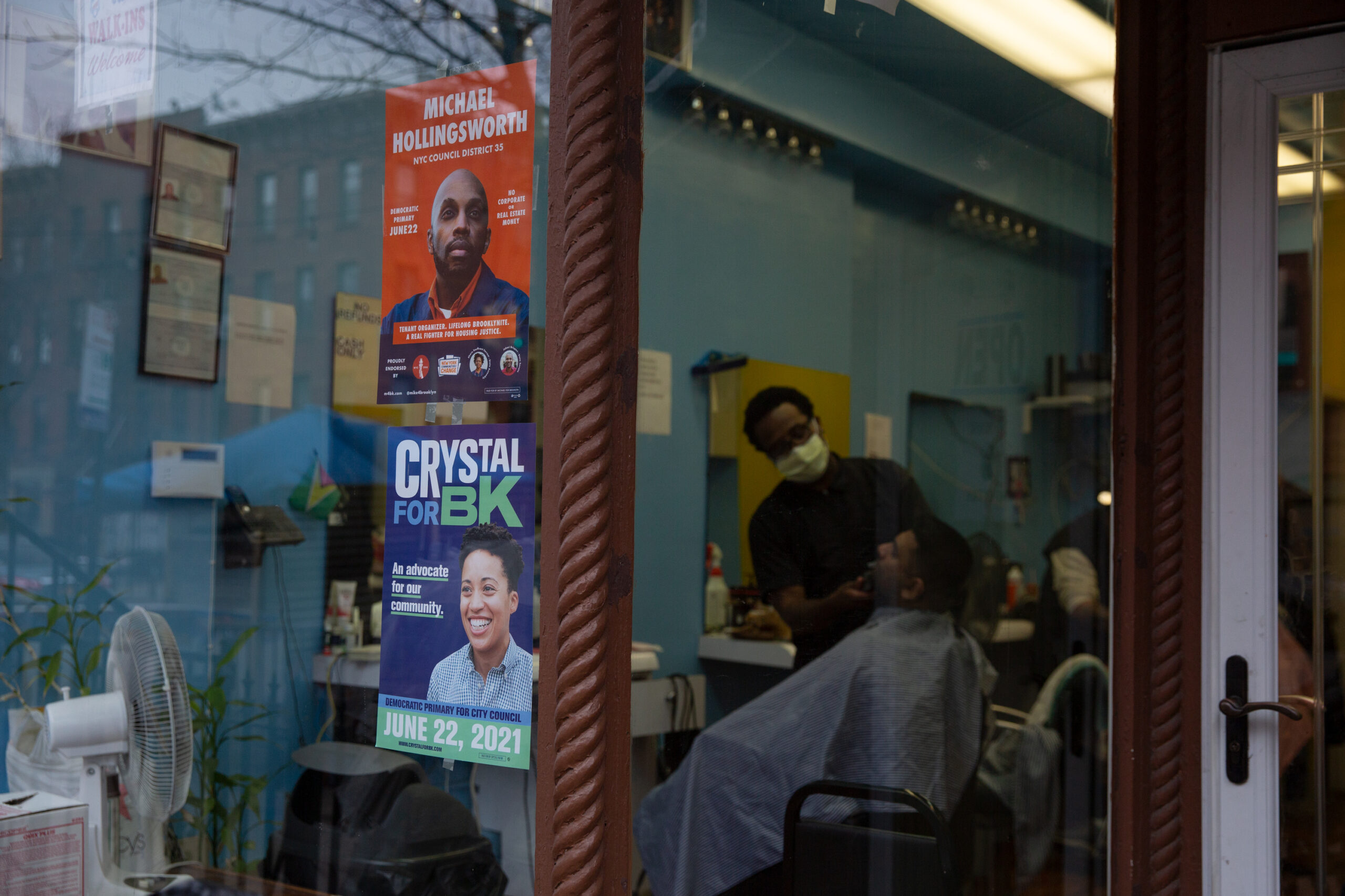 Campaign posters for Michael Hollingsworth and Crystal Hudson compete at a barbershop in Prospect Heights, Brooklyn, March 16, 2021.