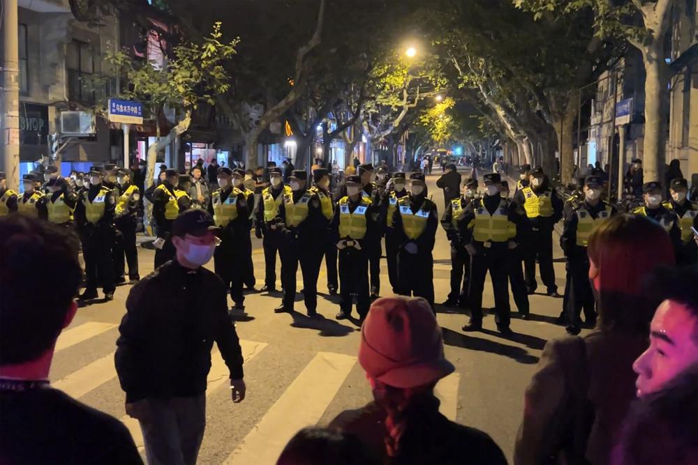 Chinese police officers block off access to a site where protesters had gathered in Shanghai on Sunday, Nov. 27, 2022. Protests against China's strict 