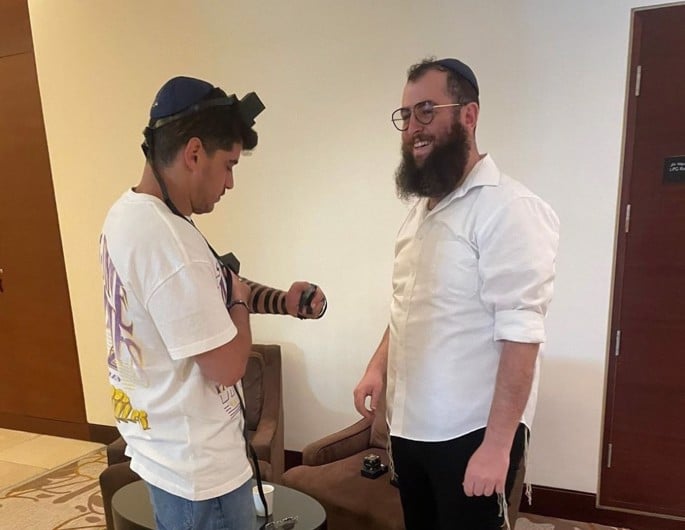 Rabbi Kogan helps Avi Batito lay tefillin.