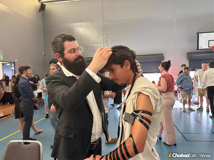 Jewish men and women took the opportunity to perform a mitzvah in memory of those killed, wrapping tefillin with yeshivah students and accepting menorahs and Shabbat candles to light at home.