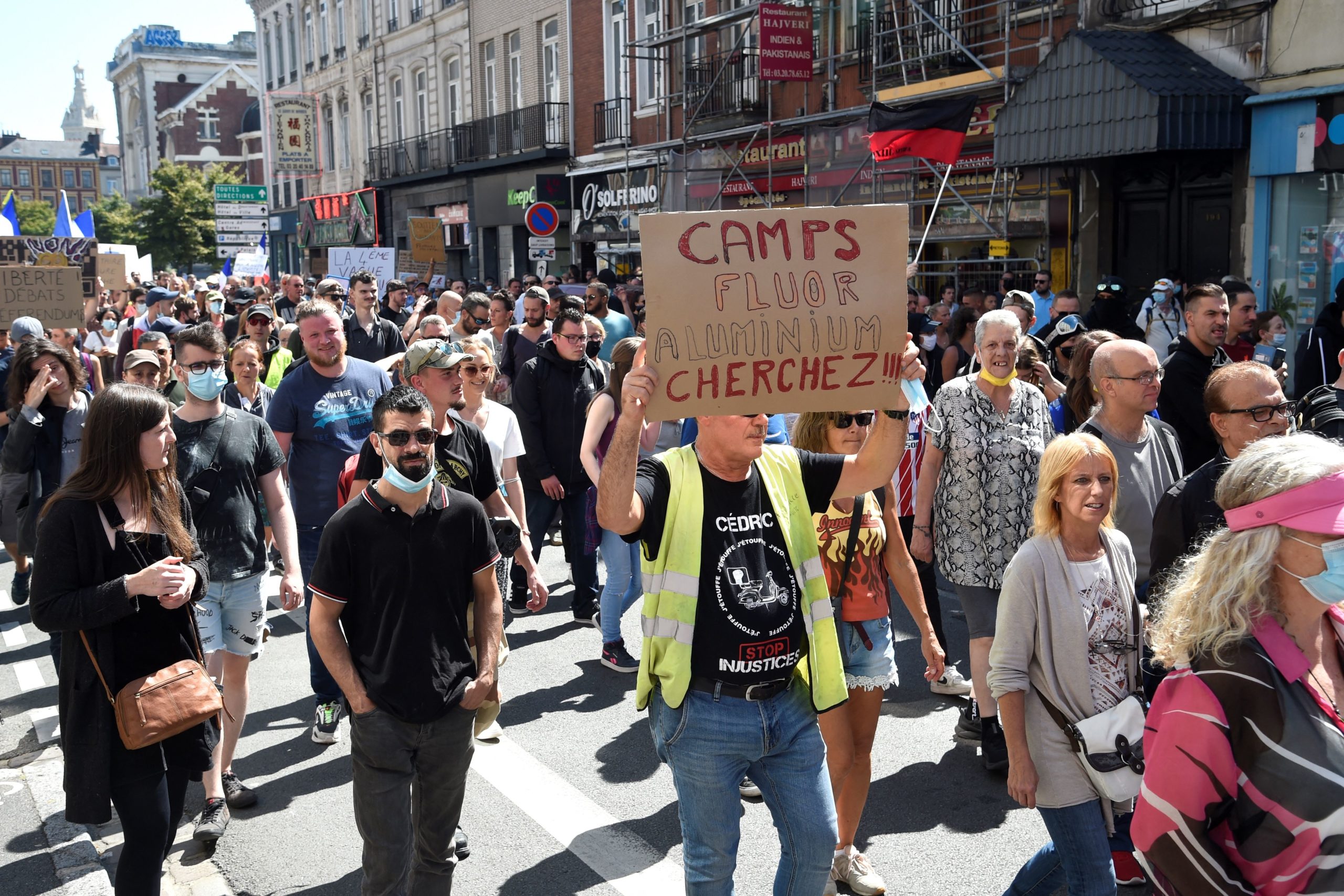 A demonstrator with a yellow vest (gilet jaune) holds up a banner which reads 'Look for fluoride, aluminium' during a national day of protest against the compulsory Covid-19 vaccination for certain workers, and the mandatory use of the health pass called for by the French government to access most public spaces, in Lille, northern France, on August 14, 2021. - France began enforcing on August 9, 2021, a Covid pass championed by President Emmanuel Macron in cafes, restaurants and trains, a tightening of rules the government hopes will boost vaccinations but which has prompted weeks of angry protests. FRANCOIS LO PRESTI/AFP via Getty Images