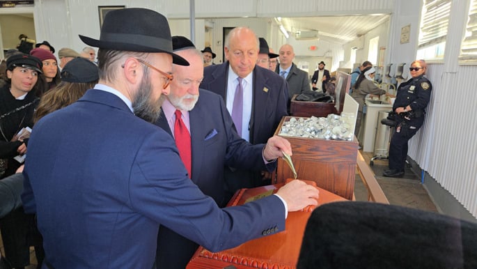 Gov. Mike Huckabbe gives charity before praying by the resting place of the Rebbe.