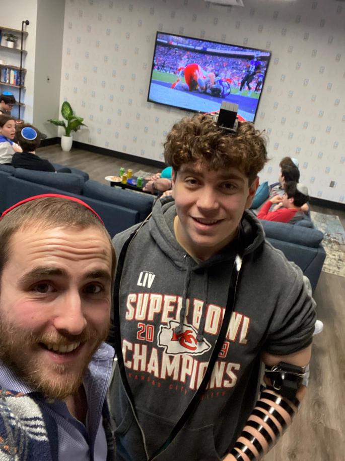 Rabbi Avremi Baron, left, and a teen take a break from the football to lay tefillin. - CTeen of Kansas City