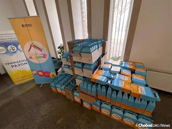 The packages contain wine, mini-sweets, fresh hamentashen, an illustrated scroll of Esther (Megillat Esther), a colorful gragger (noisemaker), and a guide detailing the holiday customs and traditions.