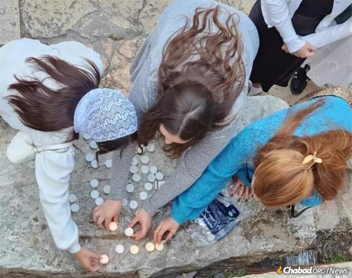 Young women light candles near the Kotel before Shabbat.