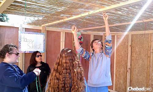 Teens finalize the roof with its sechach on top.