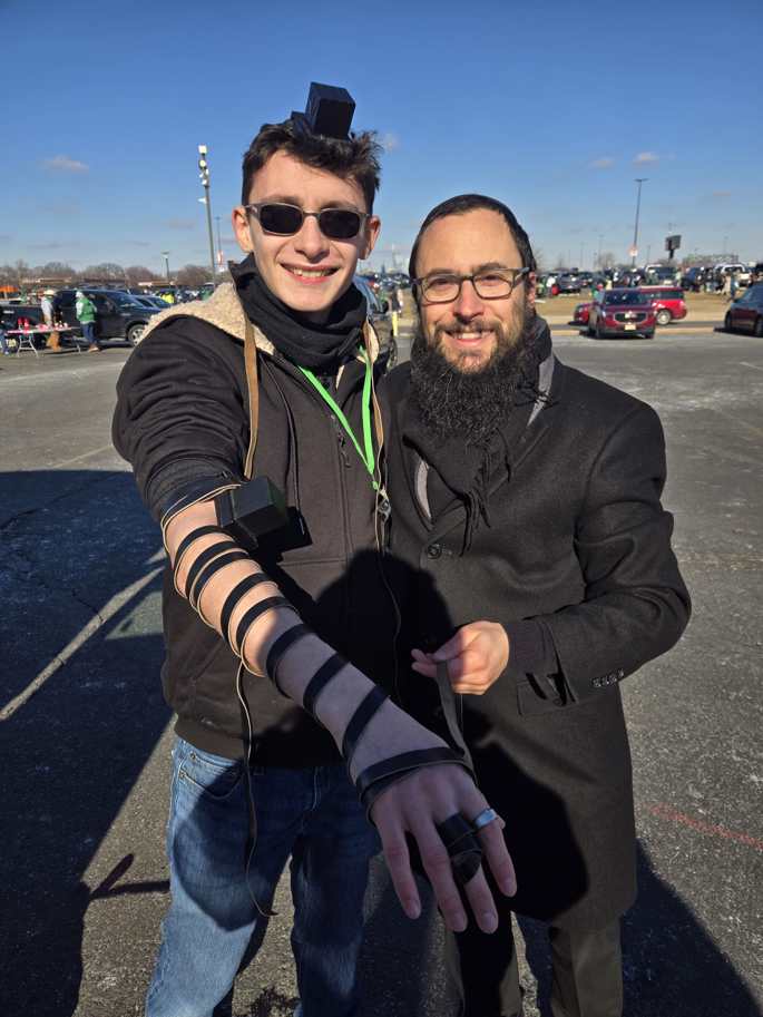 Rabbi Doniel Grodnitzky, right, helps a fan lay tefillin outside a Philadelphia Eagles football game. - Mamash Chabad