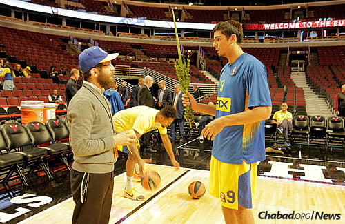 Rabbi Avraham Kagan, co-director of Chabad of River North and Fulton Market, gives a lulav and etrog to Maccabi player Itay Segev. (Photo: Yakov Studio)