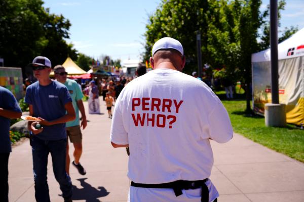 A Perry Johnson campaign staffer hands out free tickets to Iowa State Fairgoers on Aug. 11 to the underdog Republican presidential candidate’s ‘Restore the American Dream’ rally and concert at a Des Moines waterpark featuring the country duo Big & Rich on Aug. 12. (Madalina Vasiliu/The Epoch Times)