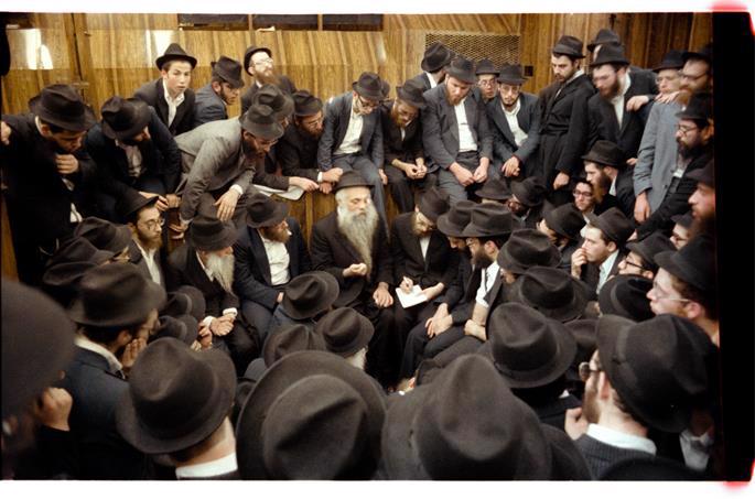 Chazarah, or repetition, following the Rebbe's farbrengen on Sept. 23, 1979. Reb Yoel is in the center, elucidating a point, while to the right, taking notes, is Rabbi Dovid Feldman, today chief editor of Lahak. Chazarah took place in the synagogue and was open to everyone. (Photo: Jewish Educational Media/The Living Archive)