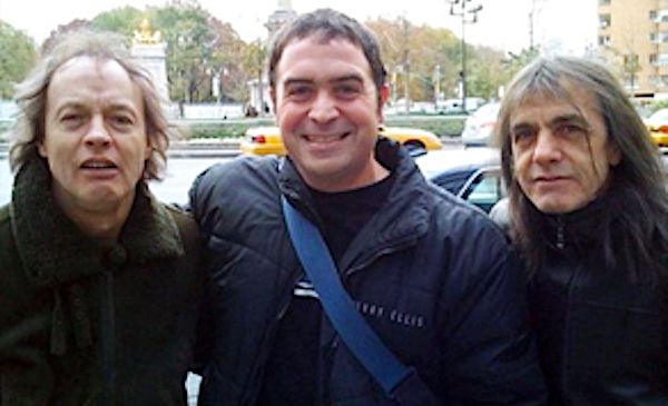 Rick Saleeby, center, poses for a photo with members of the rock group AC/DC (CNN screenshot)